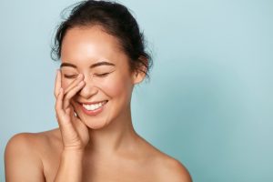 Young woman touching the skin on her face while smiling