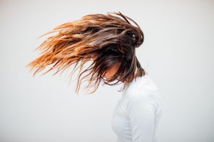 Young woman with orange highlights flipping her hair forward